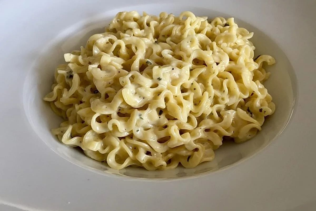 Cremige Käse Kräuter Soße in einer Pfanne, garniert mit frischen Petersilienblättchen, serviert zu Spaghetti