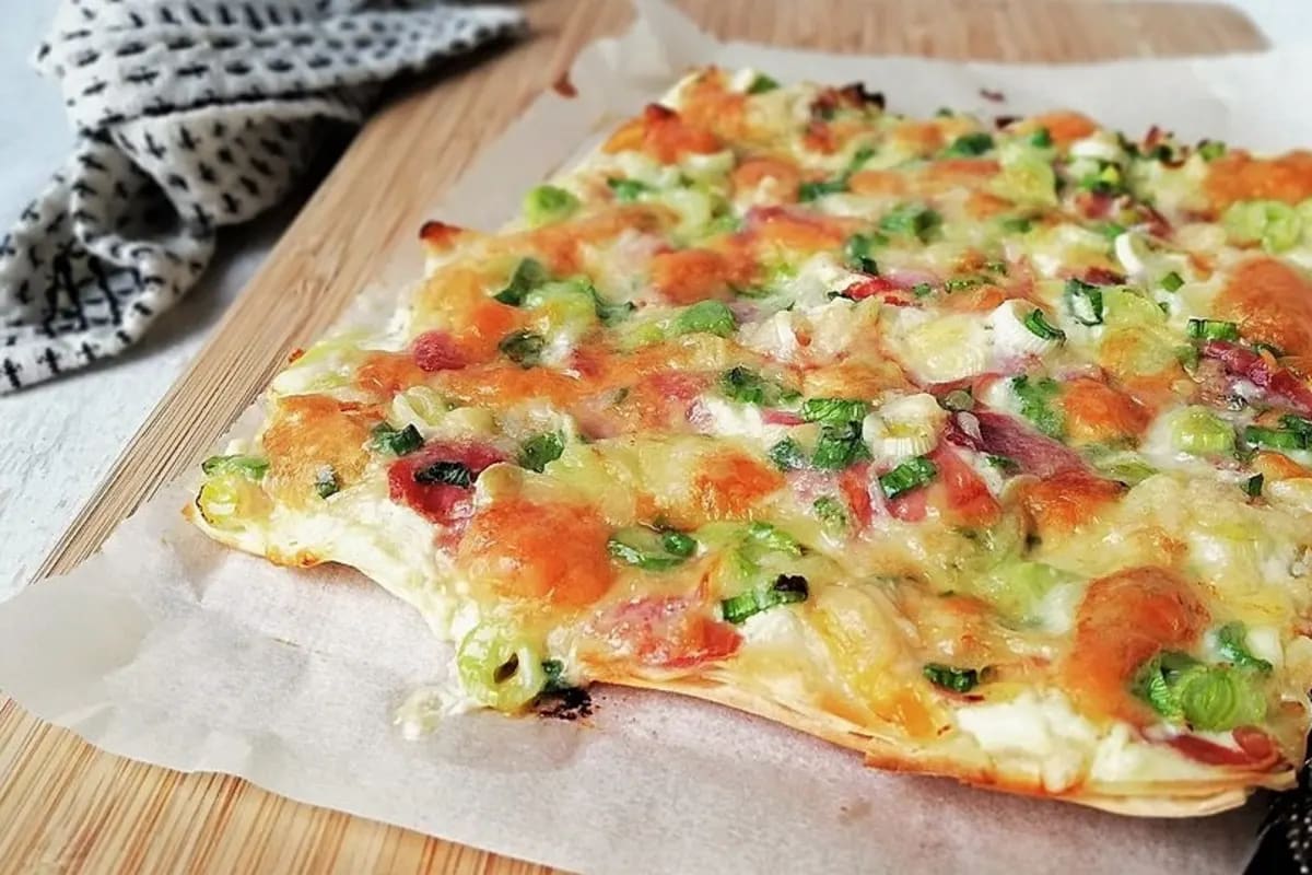 Knuspriger falscher Flammkuchen auf Yufkateig, leicht gebräunt mit dünnen Käseflocken