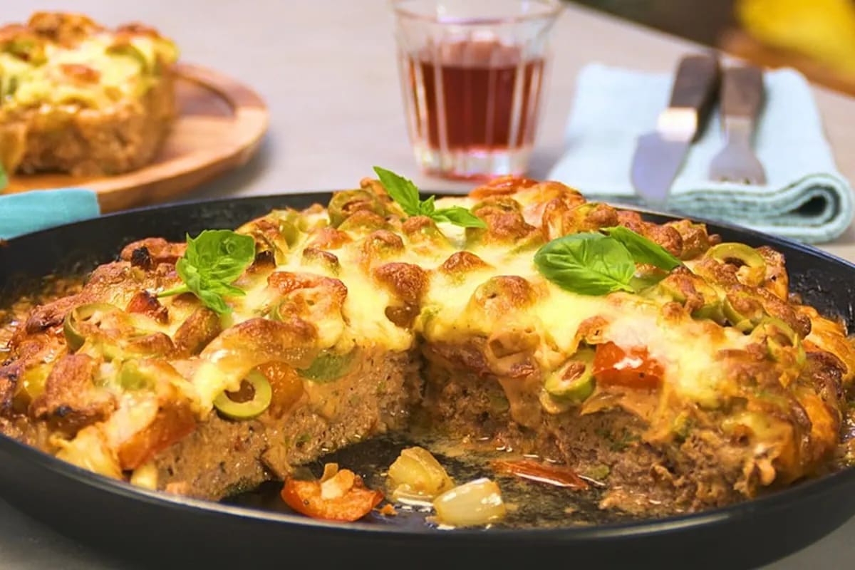 Goldbraune Fleischpizza mit geschmolzenem Käse, roter Paprika, Oliven und frischen Kräutern, aus dem Ofen genommen