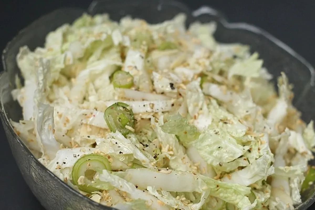 Crispy Chinakohlsalat mit goldbraunen Mienudeln, Mandeln und Sesam auf einem hellen Teller
