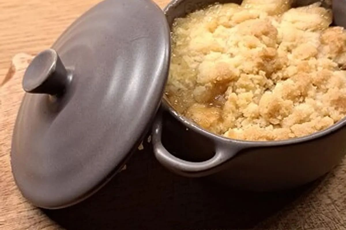 Goldbrauner Apfelcrumble mit Vanillesahne auf rustikalem Teller