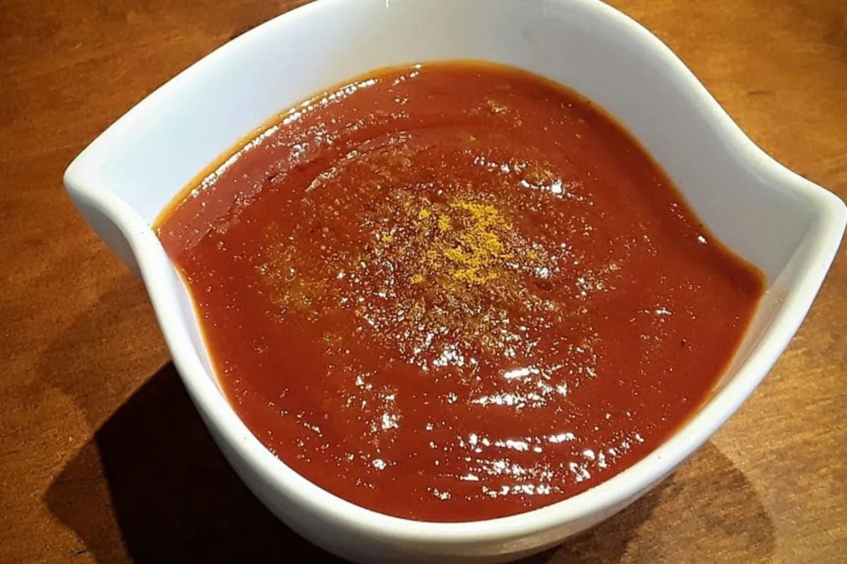 Hausgemachte westfälische Currywurst mit glänzender roter Sauce, serviert auf rustikalem Holzbrett