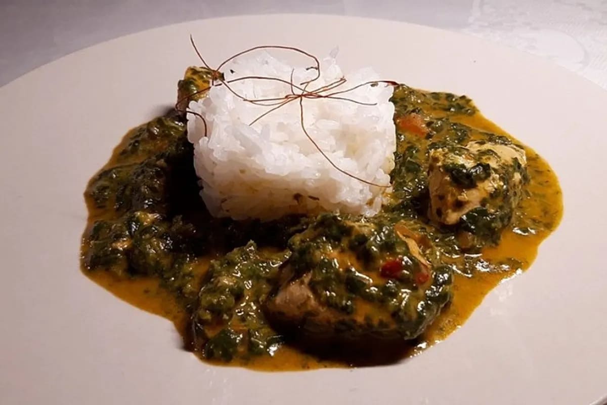Cremiges Palak Murgh mit zarten Hähnchenwürfeln, grünem Spinat und aromatischer Currysoße auf einem Teller neben Basmatireis