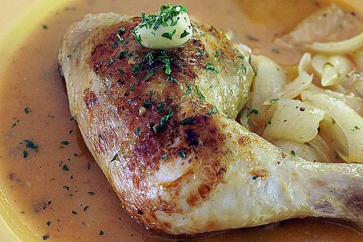 Goldbraun gebratenes Hähnchen mit Knoblauchscheiben und frischer Petersilie in einer weißen Soße