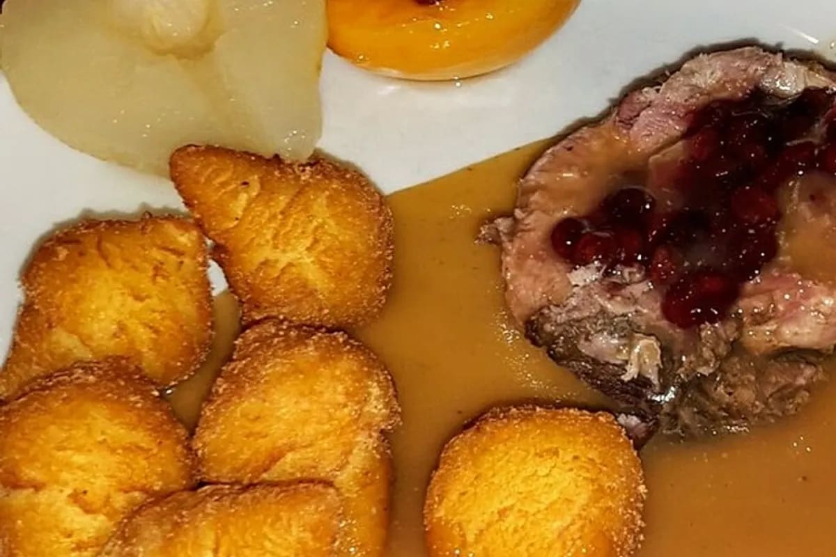 Goldbraun gebratene Wildschweinkeule mit glänzender Rotweinsauce und Preiselbeeren