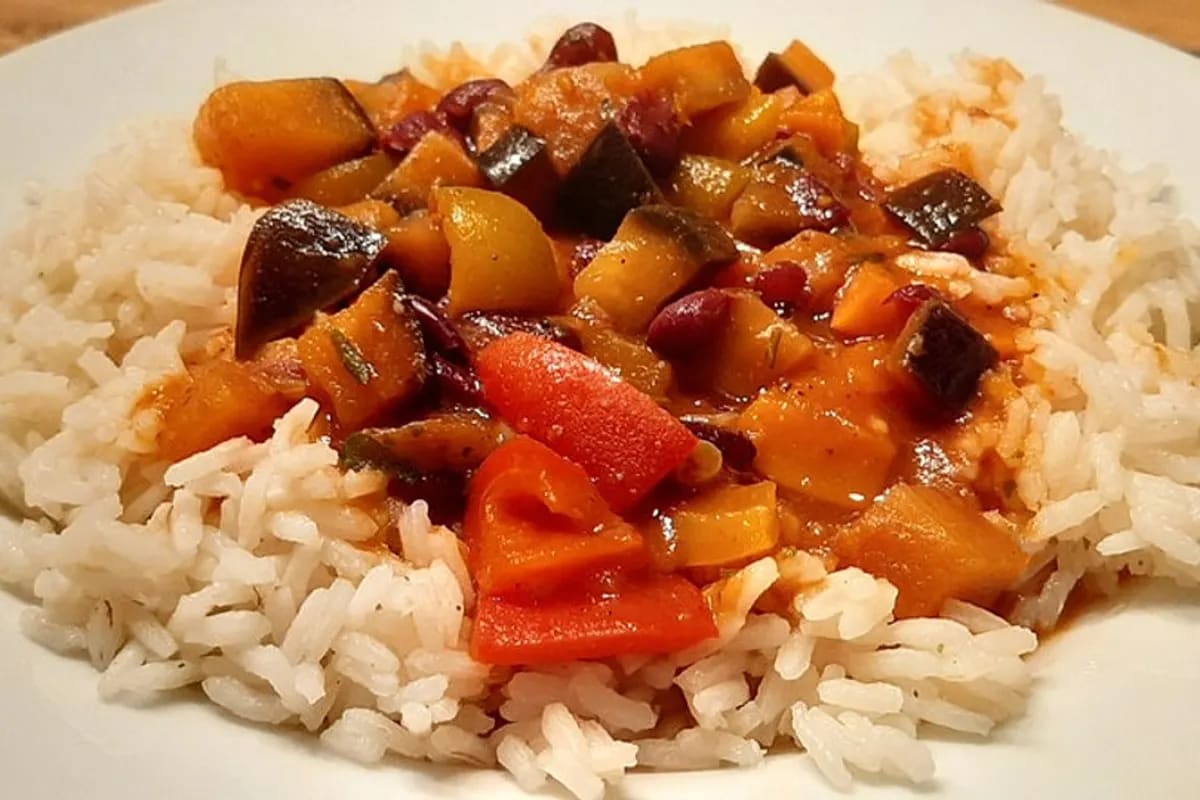 Bunte Paprika‑Gemüse‑Pfanne mit fluffigem Basmatireis auf einem weißen Teller