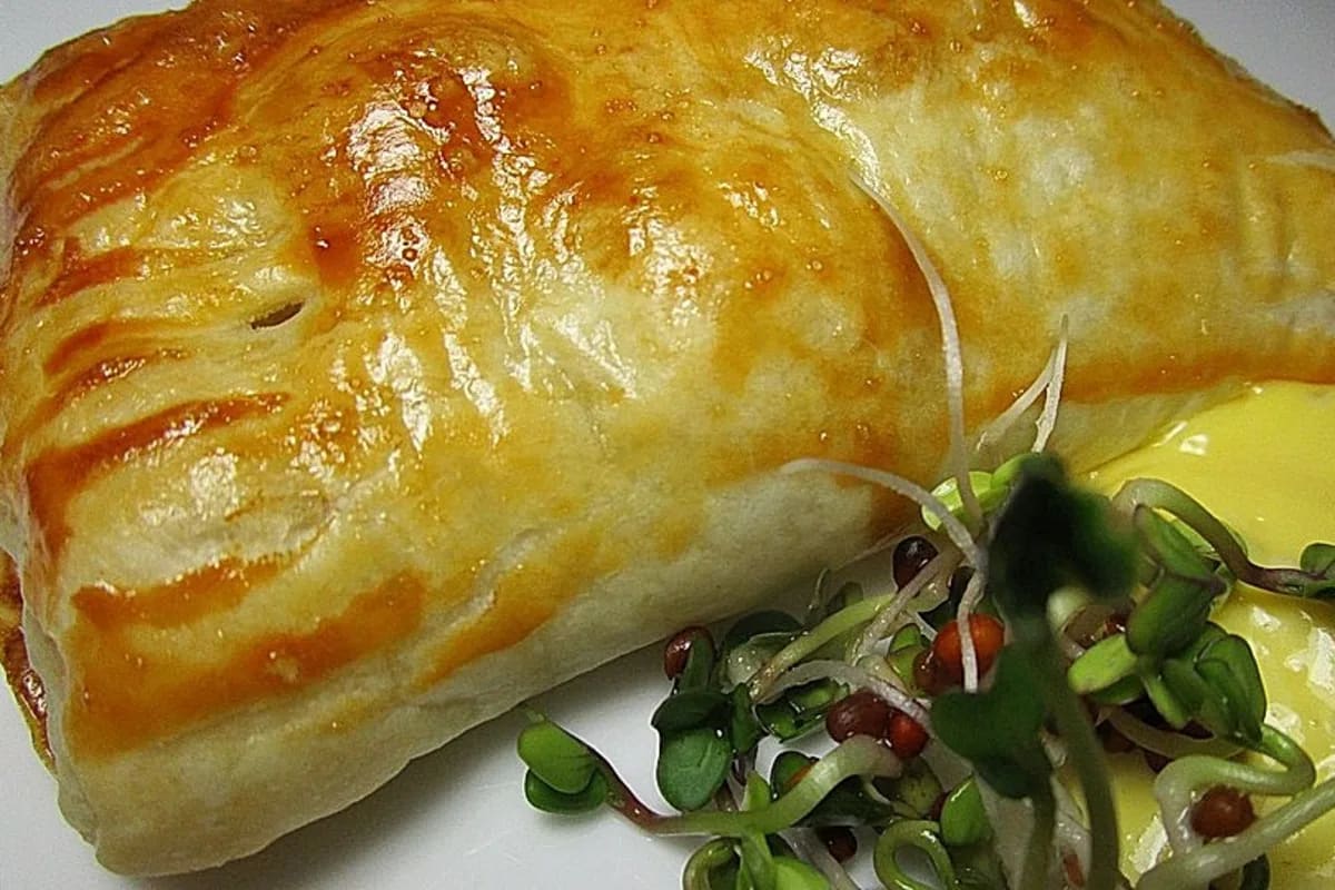 Knusprige, goldbraune Empanadas de Atún auf einem rustikalen Holzbrett mit Zitronenscheibe