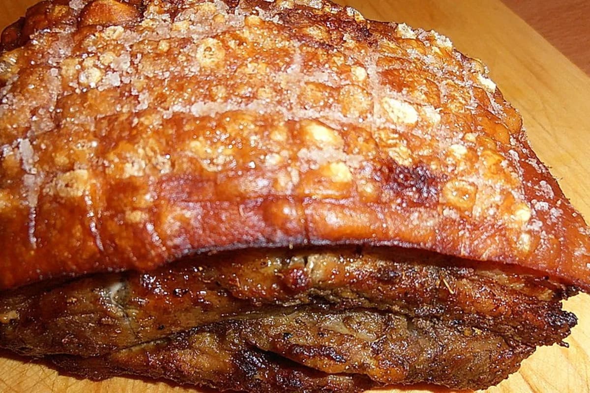 Knusprig gebackener Schweinebauch mit goldbrauner Haut, darauf Glanz von Bier-Glasur