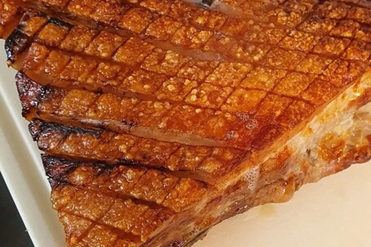 Knusprig gebratener Schweinebauch mit goldbrauner Schwarte auf Holzbrett