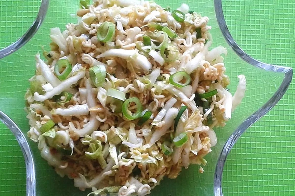 Bunter Nudelsalat mit Chinakohl, gerösteten Nüssen und frischen Frühlingszwiebeln in einer Schüssel