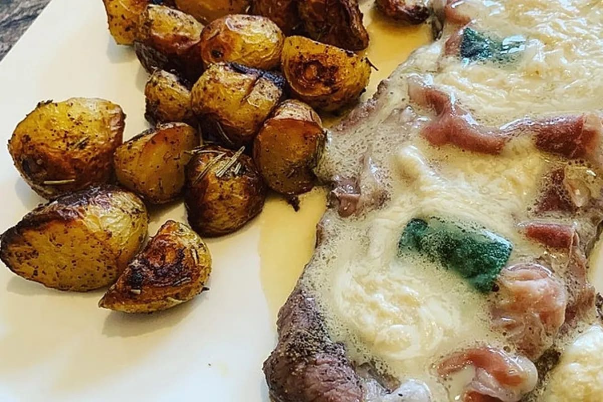 Goldbraun gebratene Kalbsschnitzel Saltimbocca mit schmelzender Buttersoße auf Holzbrett