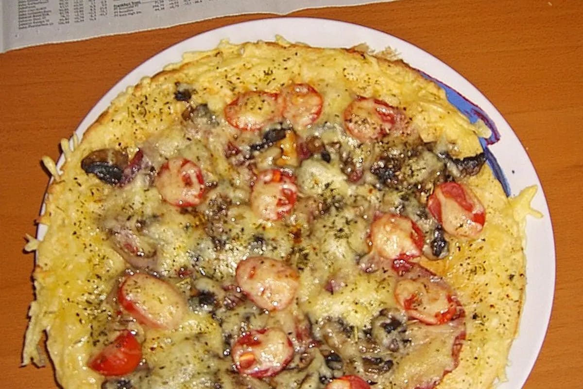 Goldbraun gebackene Pannenkoeken mit Pilz‑Zwiebel‑Belag, Salami‑ und Schinkenscheiben, Tomaten und geschmolzenem Käse, dekoriert mit frischen Kräutern