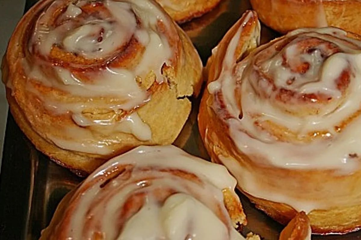 Goldbraune Cinnabon Rolls auf Backblech, bestreut mit Zimt und Zuckerguss