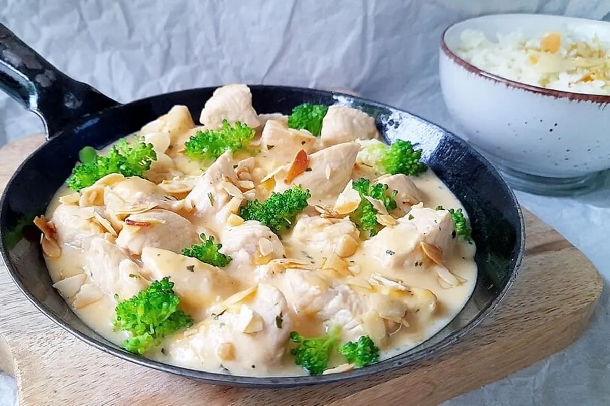 Cremige Hähnchenbrust-Brokkoli-Pfanne mit gerösteten Mandelblättchen, angerichtet in einer schwarzen Pfanne.