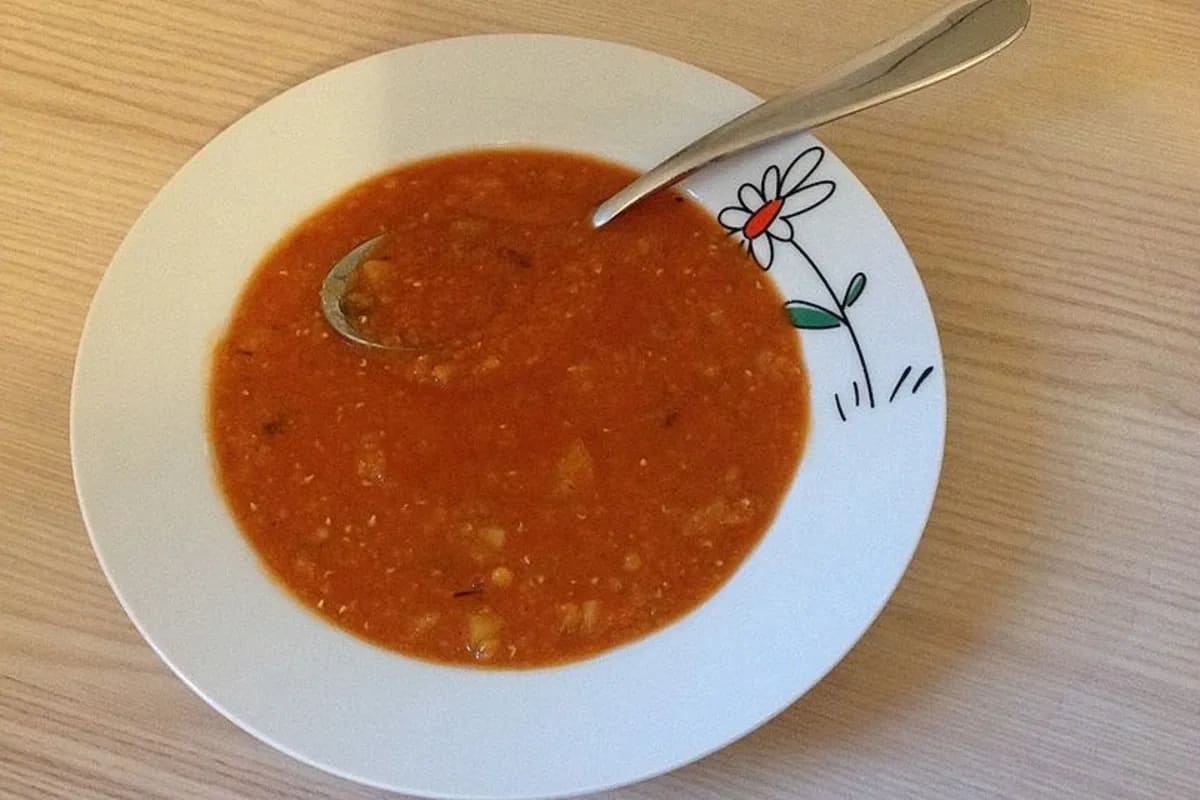 Schüssel mit rotem Linsen‑Kartoffel‑Curry, garniert mit frischem Koriander und knusprigen Mandelblättchen