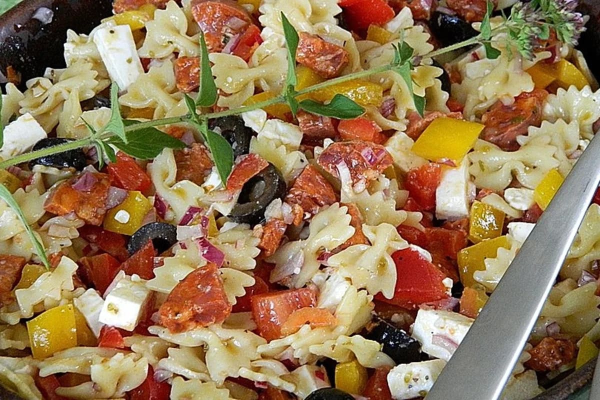 Bunter ungarischer Nudelsalat mit Paprika, Salami, Feta und Oliven in einer Schüssel