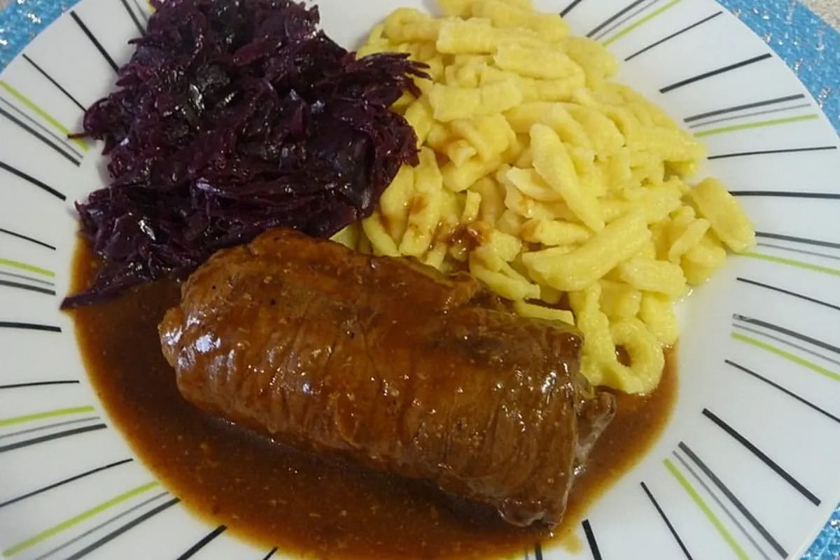 Rouladen im Schnellkochtopf, goldbraun angebraten, umgeben von Gemüse und Sauce