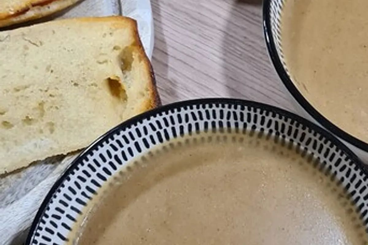 Schüssel mit dampfender Brotsuppe, garniert mit Petersilie und knusprigen Brotstücken