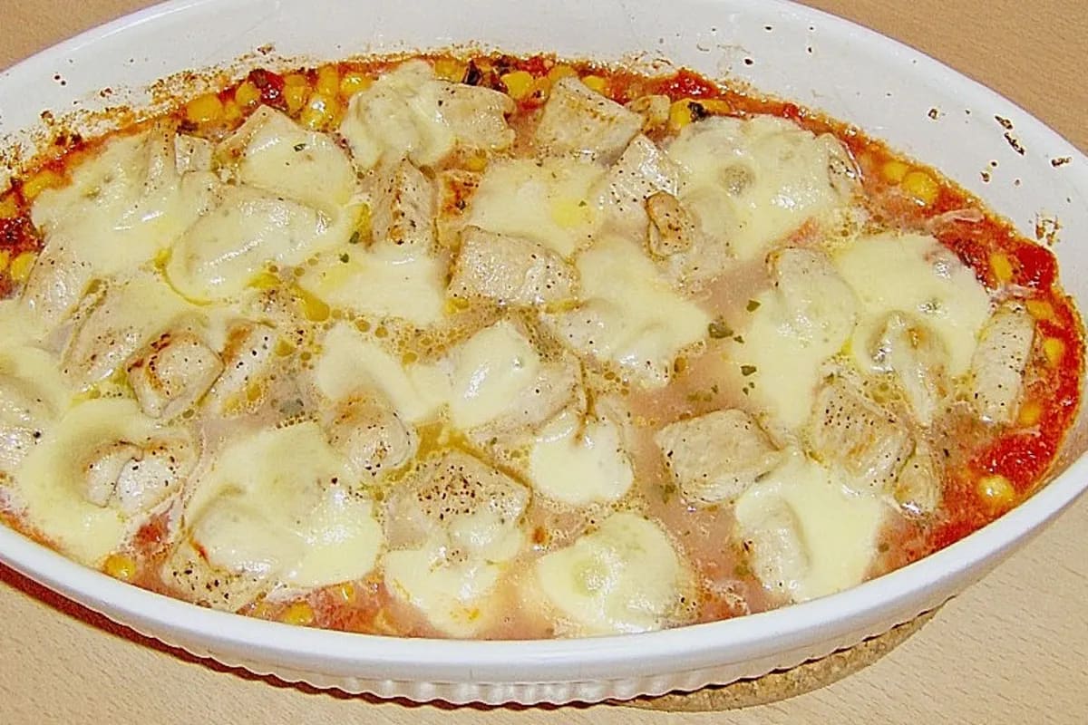 Knusprig überbackenes Putenschnitzel mit roter Tomatenscheibe und geschmolzenem Mozzarella in einer Auflaufform