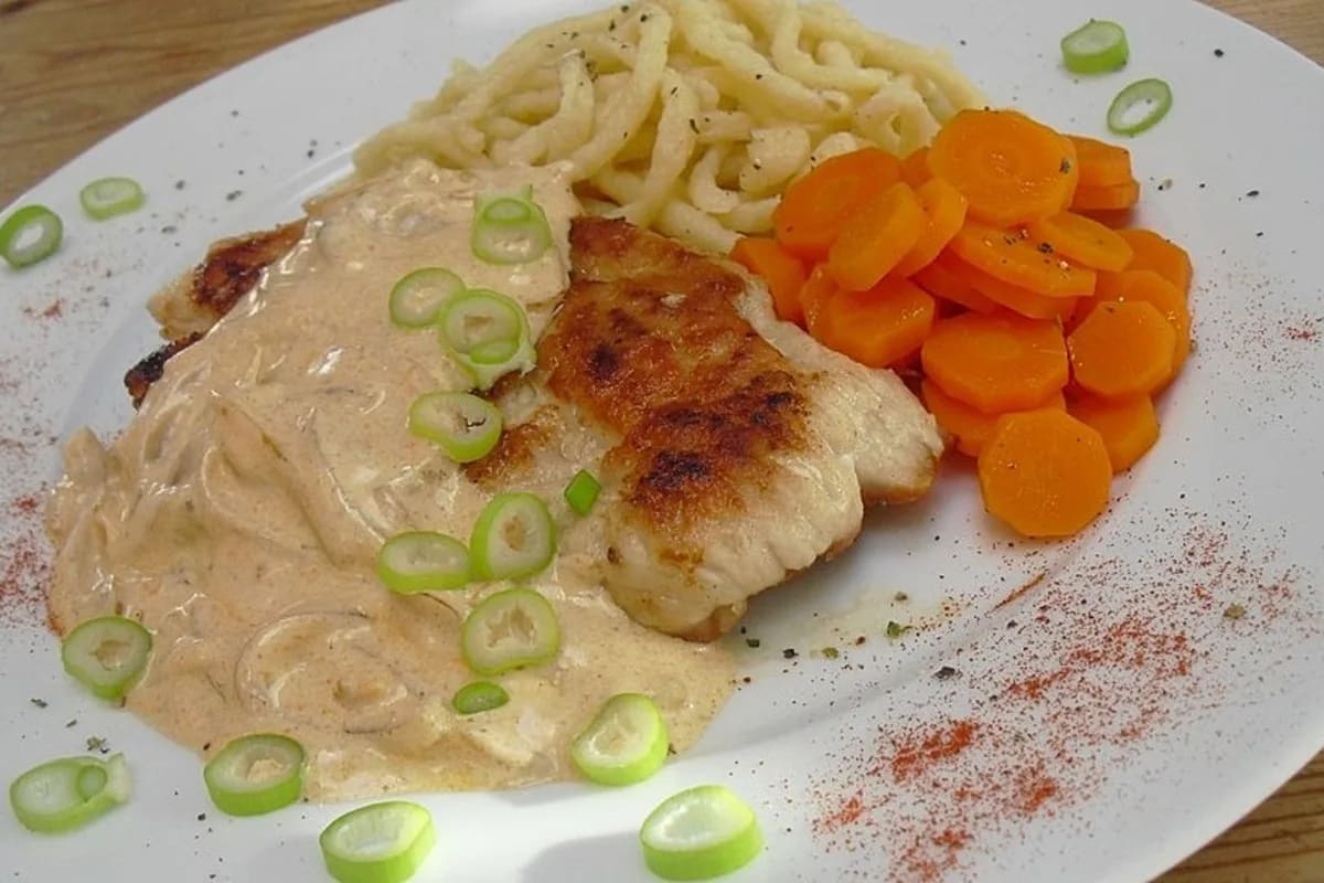 Goldbraun gebratenes Schnitzel in cremiger Zwiebelsauce auf einem Teller