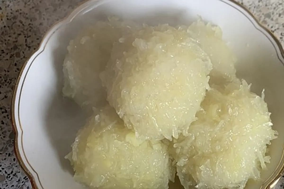 Grüne Klöße schwimmen in einem Topf, umgeben von frischer Petersilie und einer dunklen Bratensauce