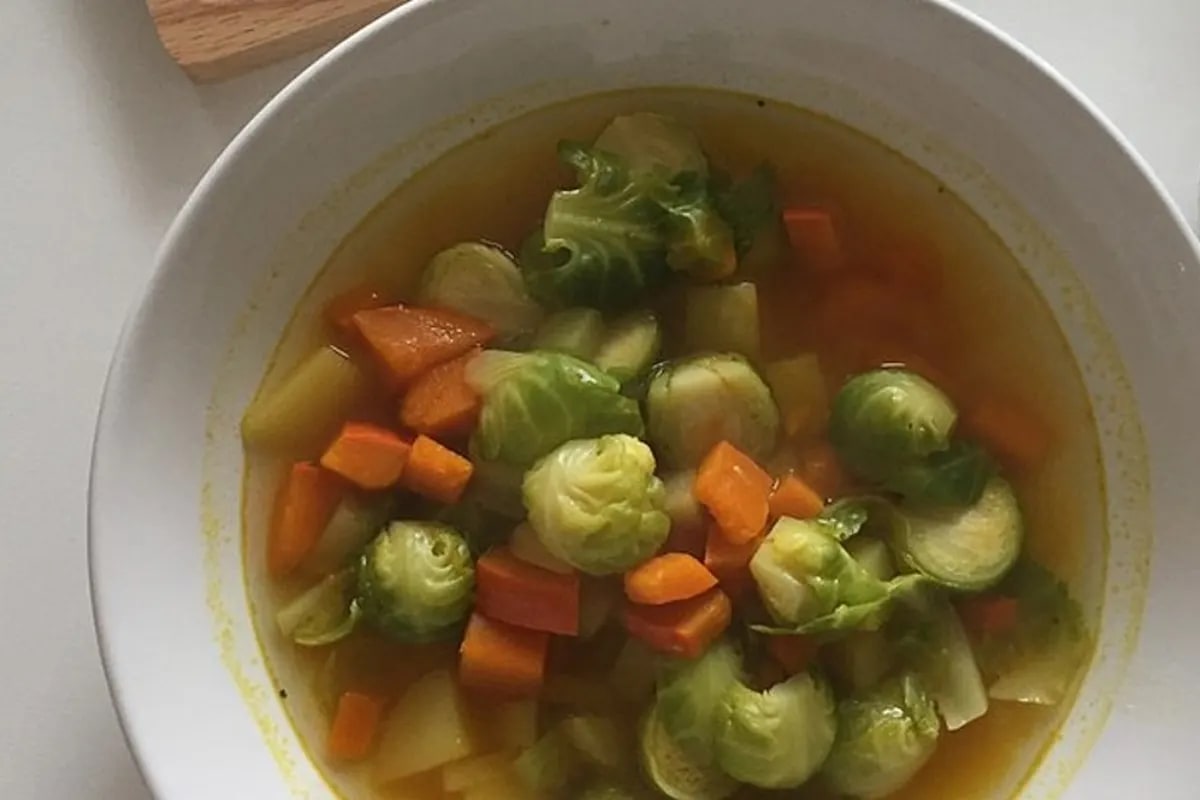 Rosenkohl-Kürbis-Eintopf in einem rustikalen Topf, garniert mit frischer Petersilie