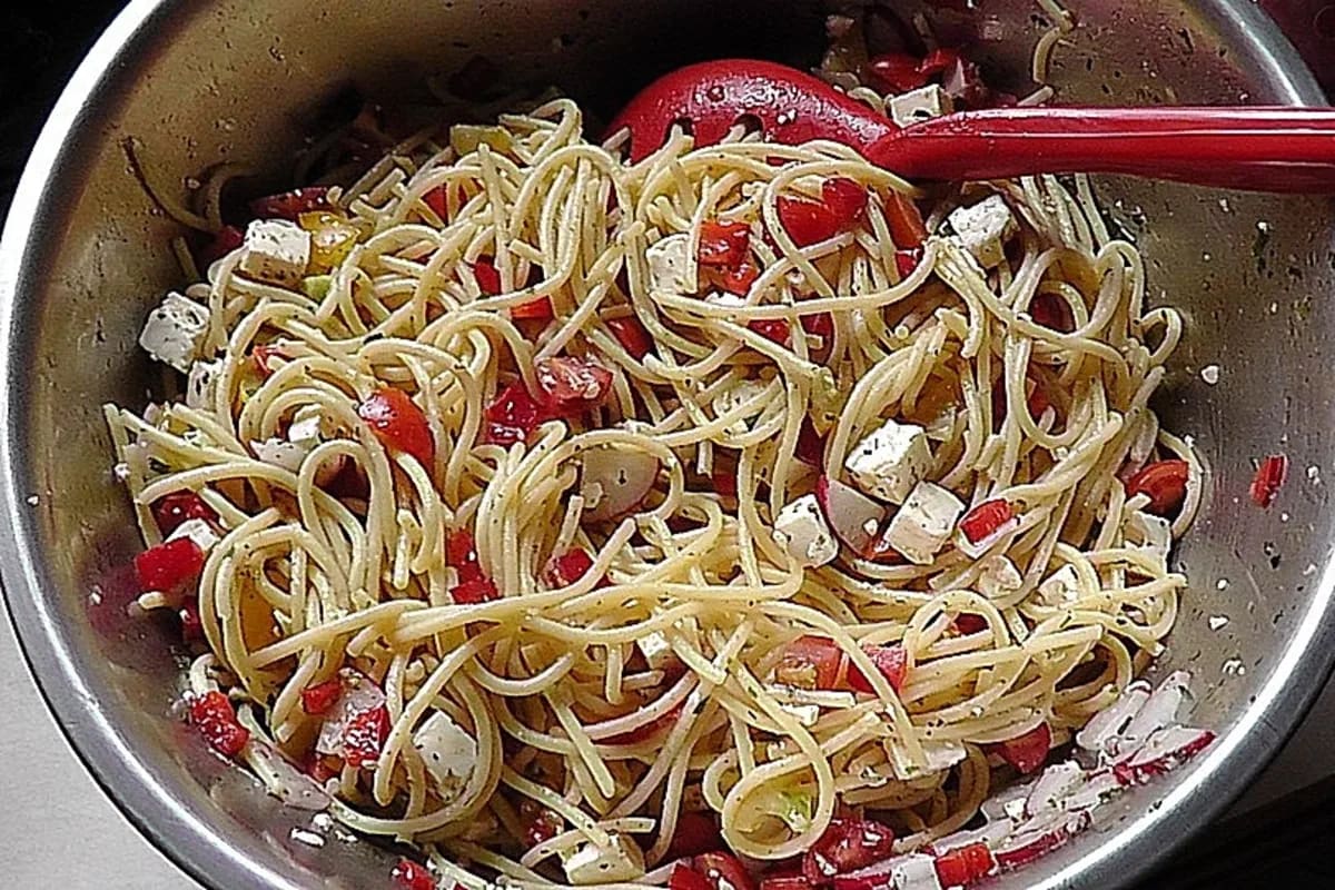 Knoblauch‑Nudelsalat mit buntem Paprika, Cherrytomaten und zerbröckeltem Feta auf einer rustikalen Holzplatte