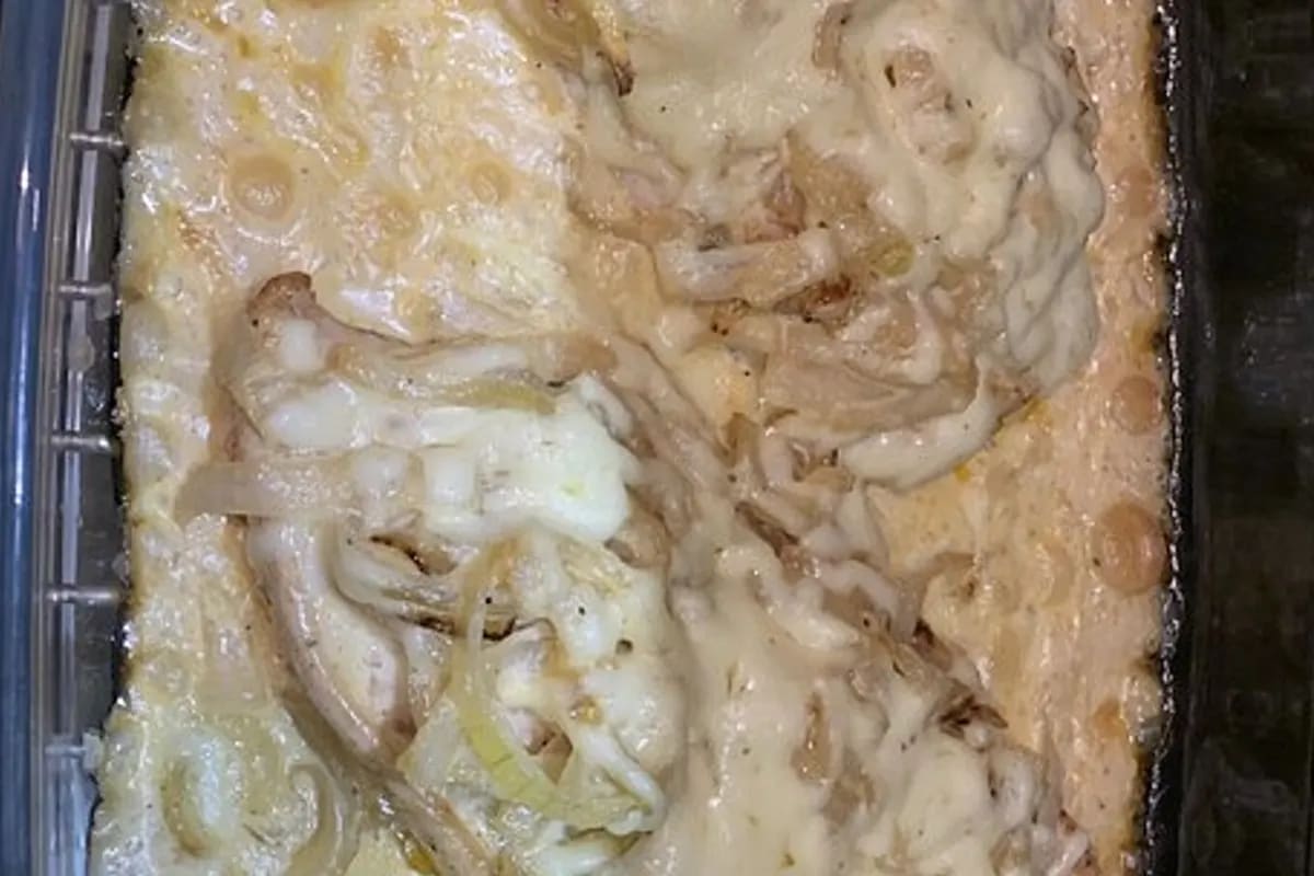 Knuspriges Schnitzel mit goldbraun geschmolzenem Käse und cremiger Zwiebelsauce, serviert neben Baguette