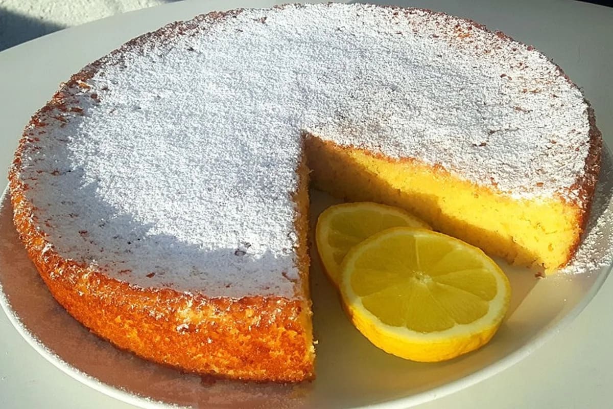 Goldbrauner italienischer Zitronenkuchen mit Zitronenzesten auf einem weißen Teller