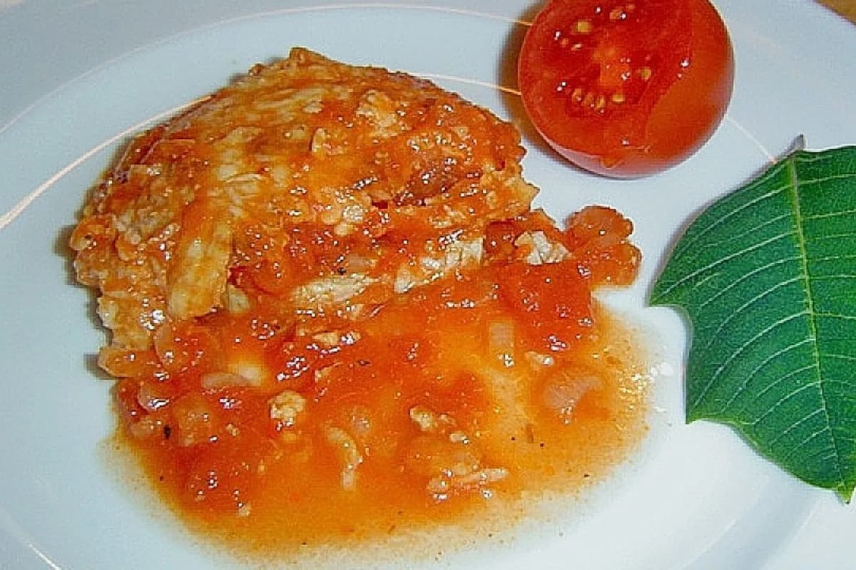 Goldbraun überbackenes Schweinefilet mit Tomatensauce und geschmolzenem Käse, daneben knusprige Baguettescheiben