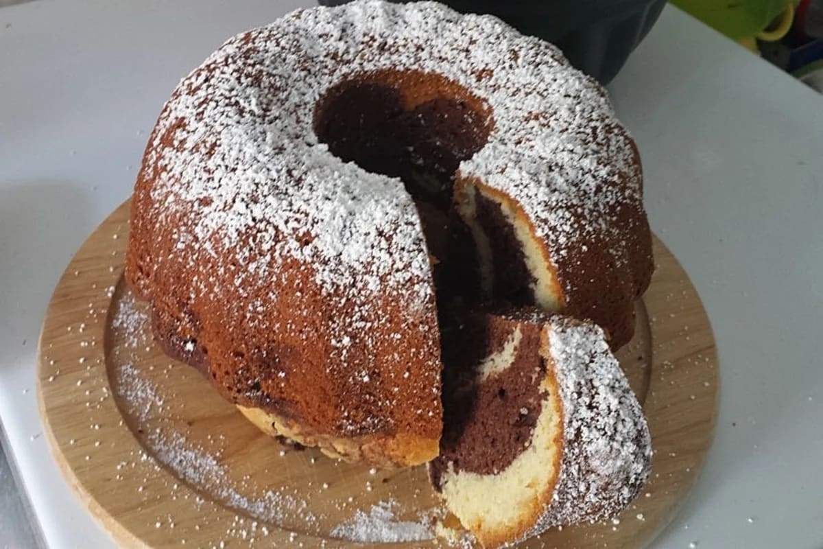Goldbrauner Marmorkuchen mit saftiger Sahne, auf einem weißen Teller angerichtet, daneben ein Glas Milch
