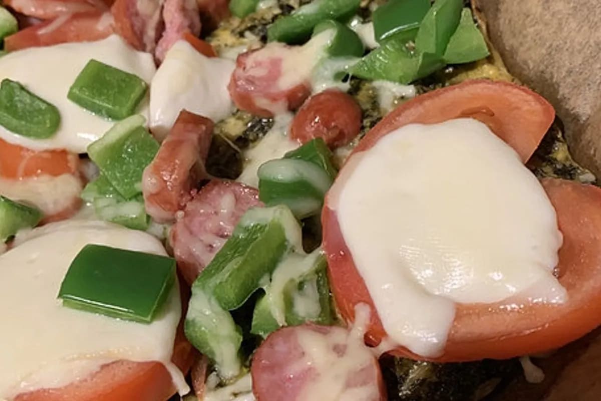 Selbstgemachte Grünkohl Pizza mit knusprigem Rand, rotem Pinkel und goldbraunen Mettenden, aus dem Ofen genommen