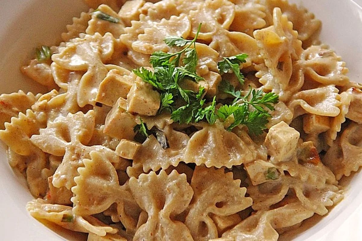 Nahaufnahme einer cremigen veganen Nudelsauce mit goldbraunem Räuchertofu und bestreut mit Hefeflocken
