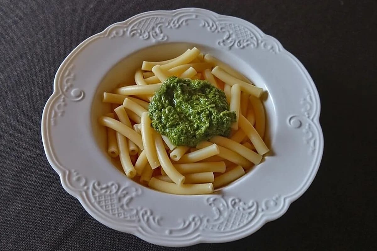 Grünes veganes Bärlauch-Pesto in einem Glas, daneben geröstete Pinien- und Sonnenblumenkerne