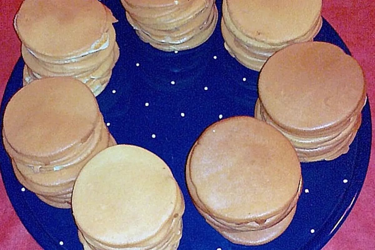 Goldbraune kleine Pancakes mit Frischkäse und Räucherlachs auf einem rustikalen Holzbrett