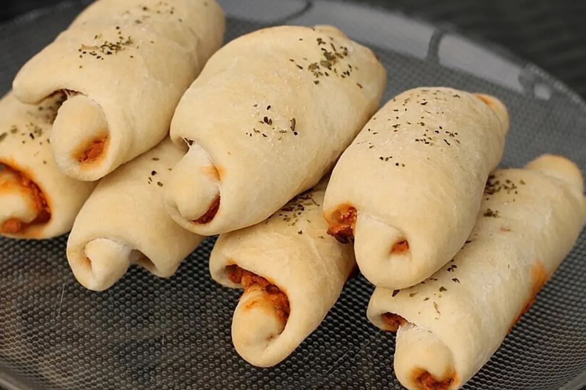 Goldbraune Pizzabrötchen mit geschmolzener Käsefüllung, angerichtet auf einem Holzbrett