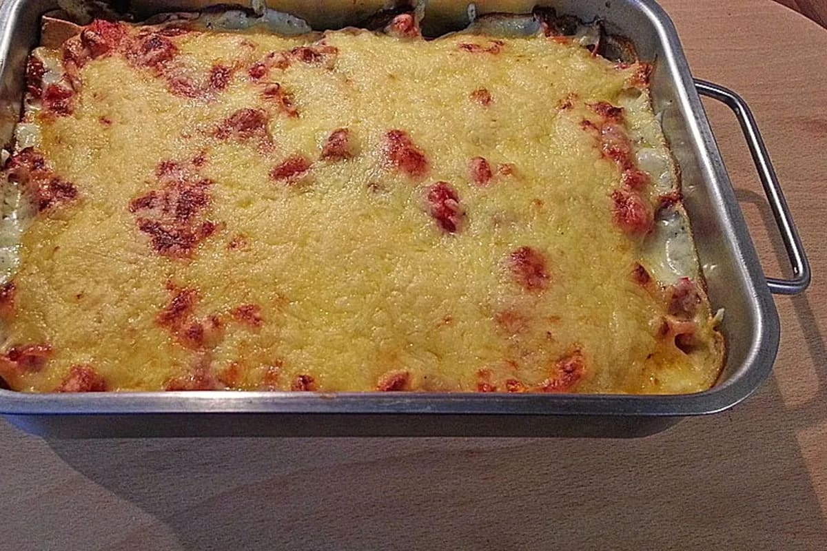 Überbackene Ofen‑Tortillas mit goldbraunem Käse, gefüllt mit Thunfisch, Tomaten und geschmolzener Béchamel, angerichtet in einer Auflaufform