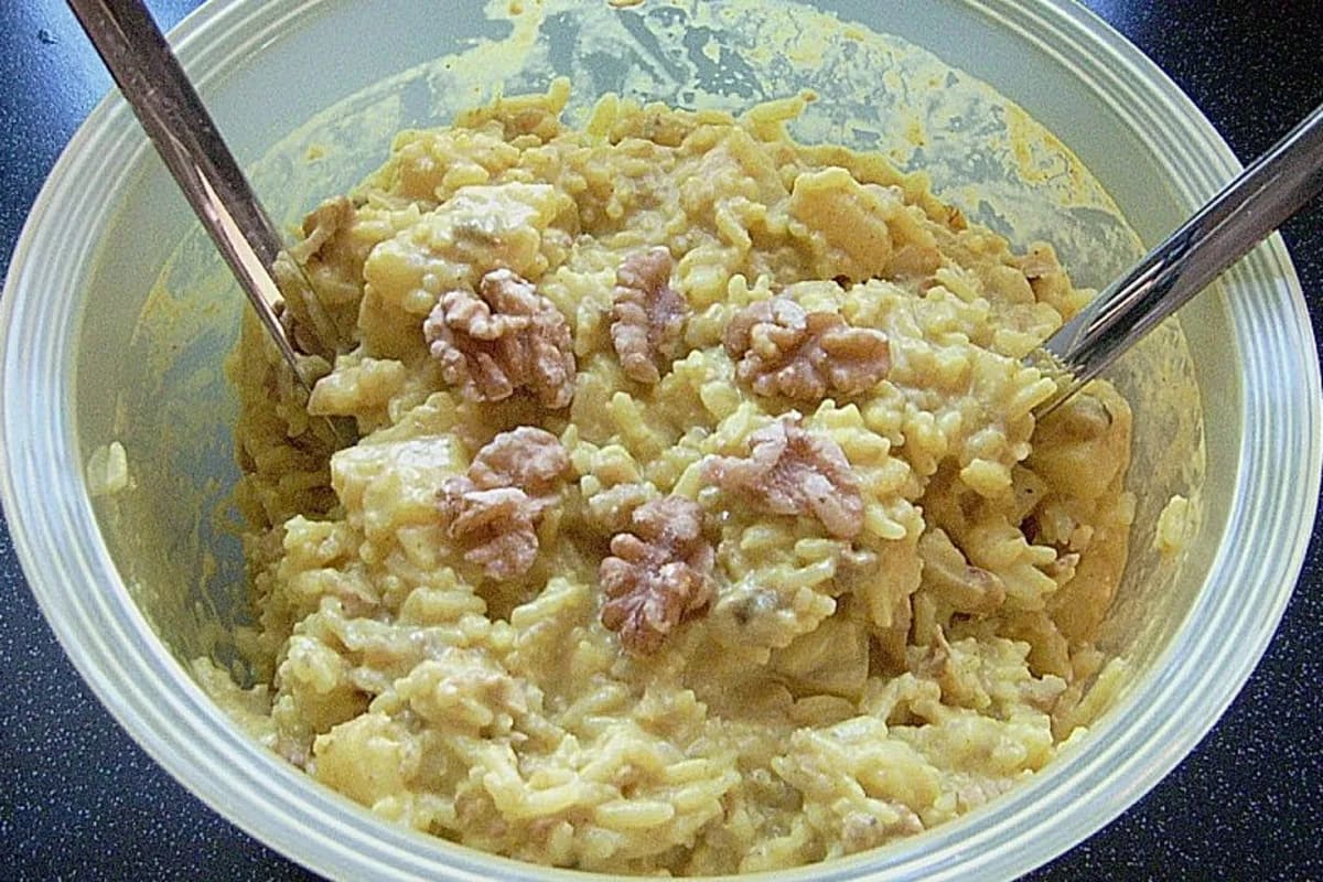 Bunter Reissalat mit gelben Currypulverstücken, Ananaswürfeln und Bananenscheiben, angerichtet in einer Schüssel