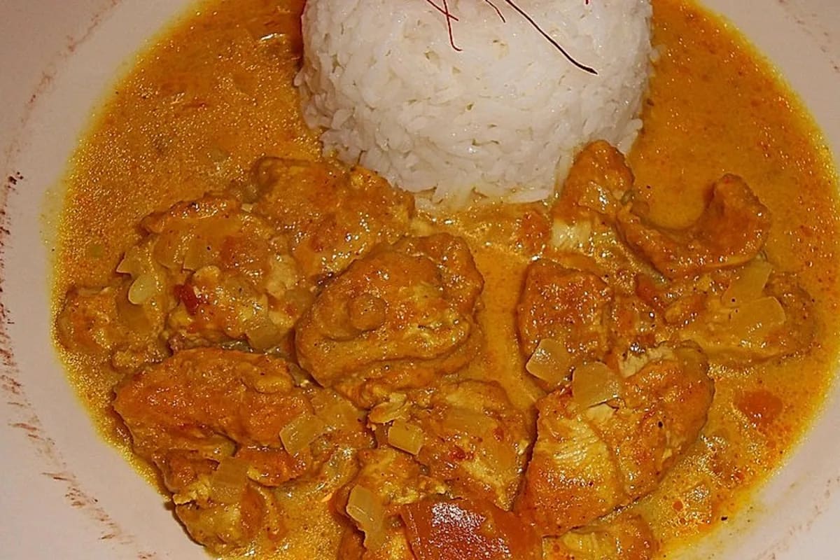 Goldbraun gebratenes indisches Hähnchen in cremiger Mangosauce, garniert mit frischem Koriander