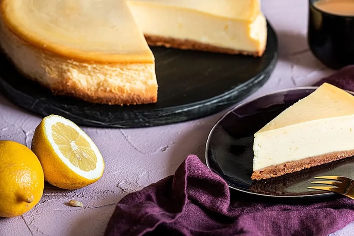 Gekühlter New York Cheesecake auf einem weißen Teller, dekoriert mit frischen Erdbeerscheiben