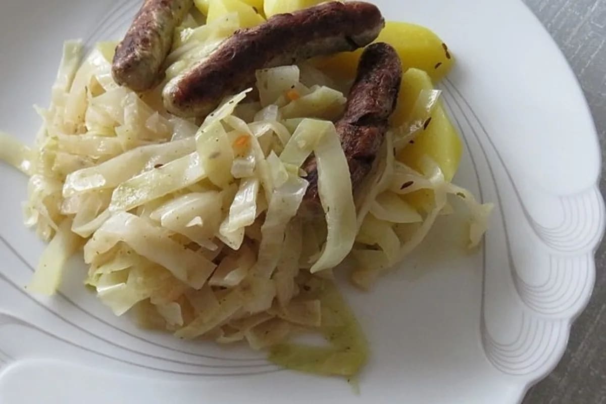 Gedünstetes Weißkraut bayrisch in einer Keramikschüssel, glänzend mit Essig‑Glasur und frischem Kümmel bestreut