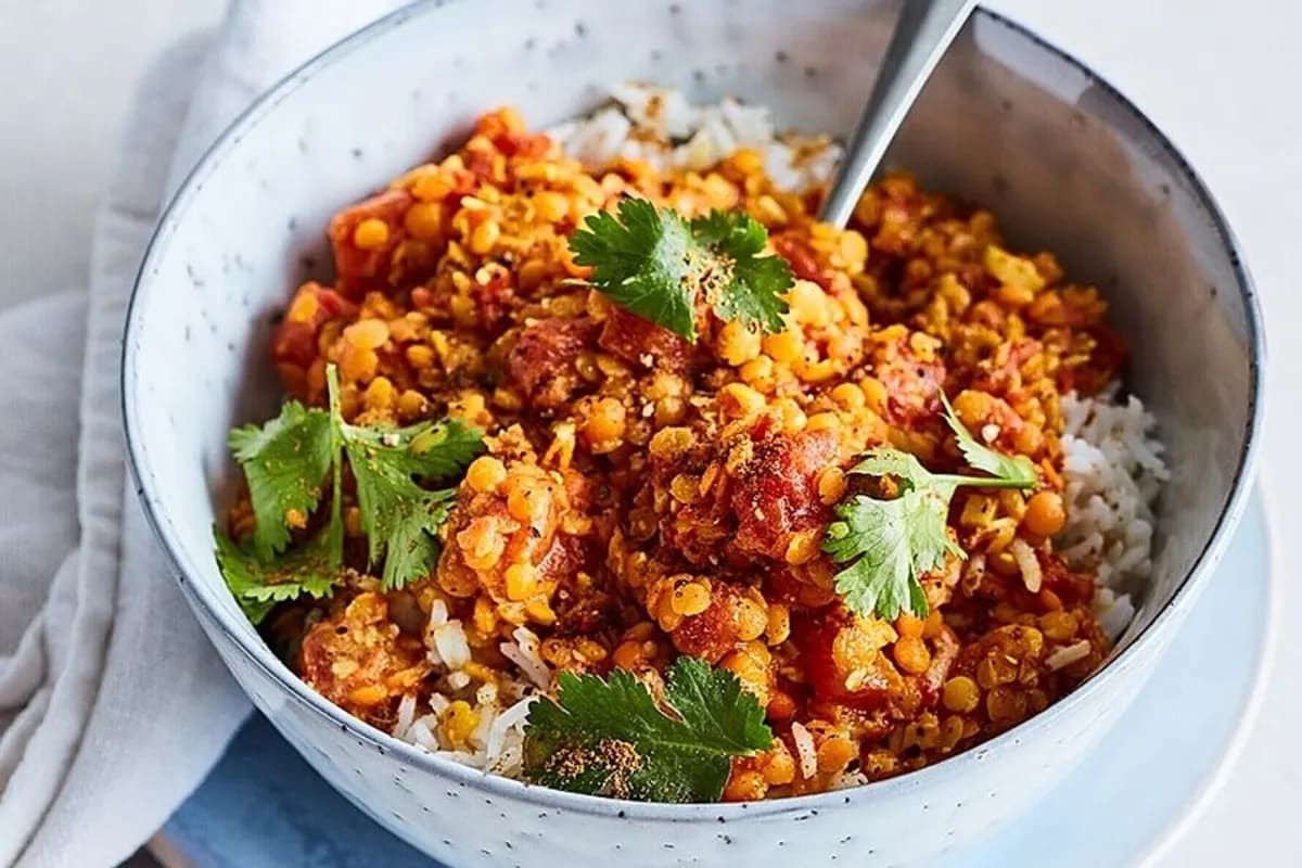 Schale mit cremigem roten Linsen-Curry, garniert mit frischem Koriander und Basmatireis