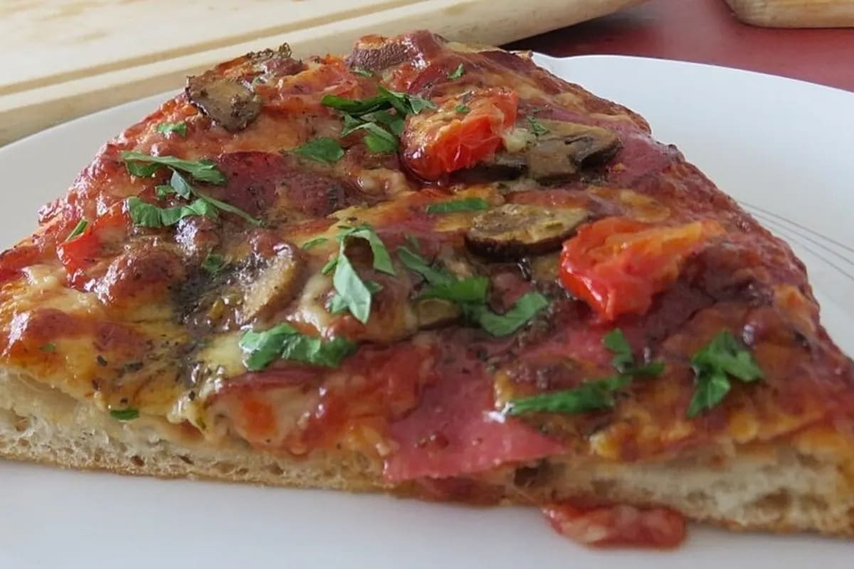 Goldbraune Pinsa mit Salami, Tomaten und geschmolzenem Käse auf Holzbrett