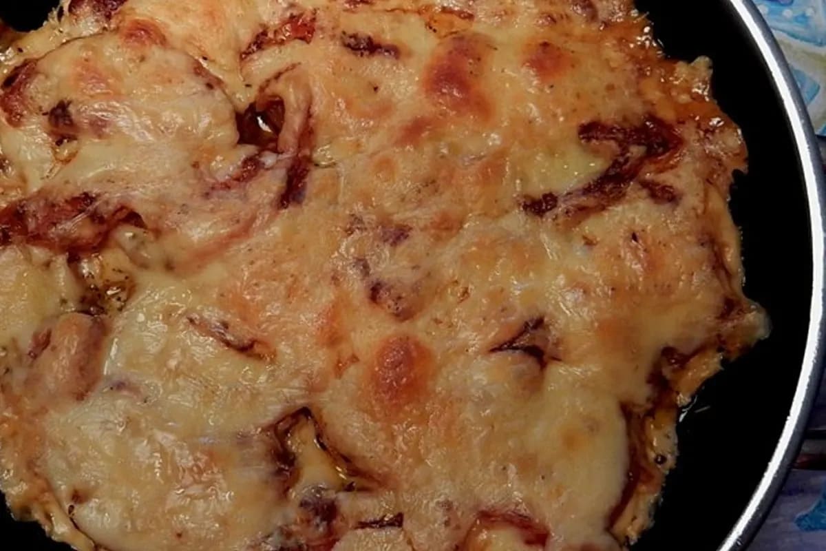 Goldbraun überbackenes Putenschnitzel mit Tomatenscheiben und geschmolzenem Käse, serviert neben fluffigen Spätzle
