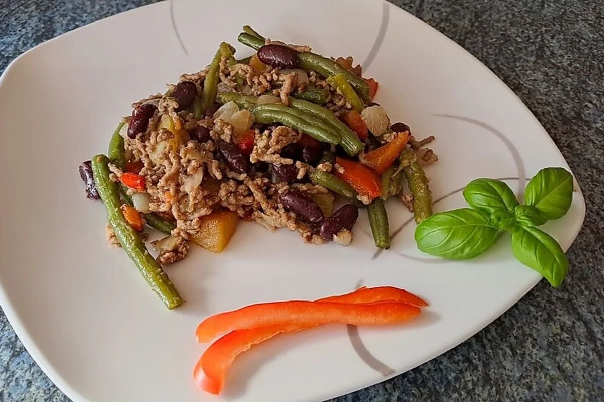 Tex-Mex-Pfanne mit Hackfleisch, Paprika, grünen Bohnen und Kidneybohnen, serviert in einer schwarzen Pfanne