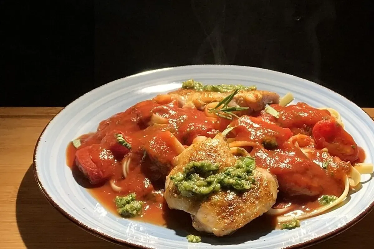 Goldbraun gebratene, ausgelöste Hähnchenschenkel mit knuspriger Haut und frischen Basilikumblättern