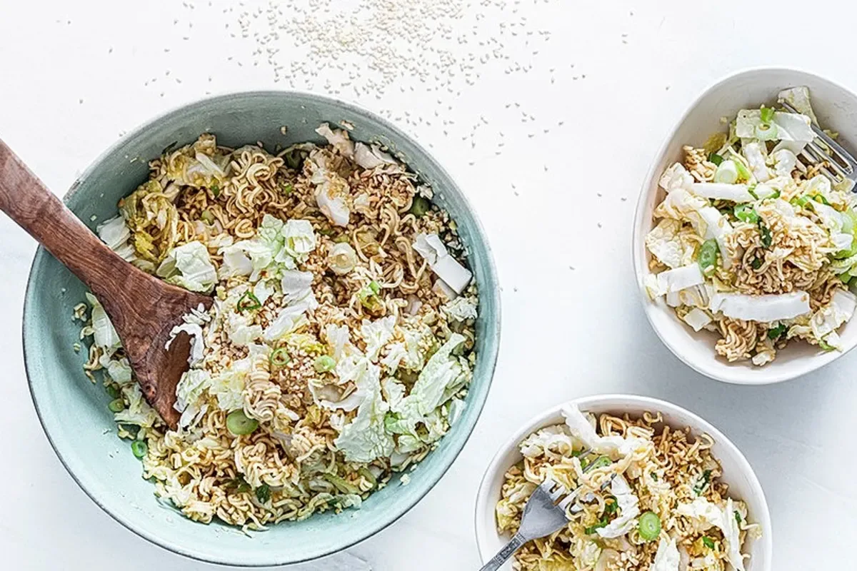 Bunter Chinakohl-Salat mit gerösteten Mandeln, Sesam, ungekochten Nudeln und Zitronenscheibe