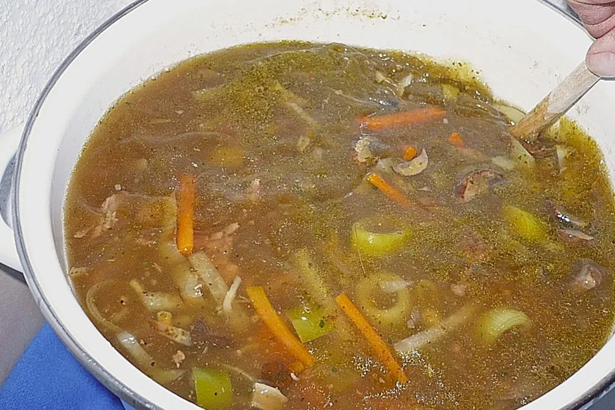 Schüssel mit dampfender Wildsuppe, garniert mit frischen Kräutern und rustikalem Vollkornbrot