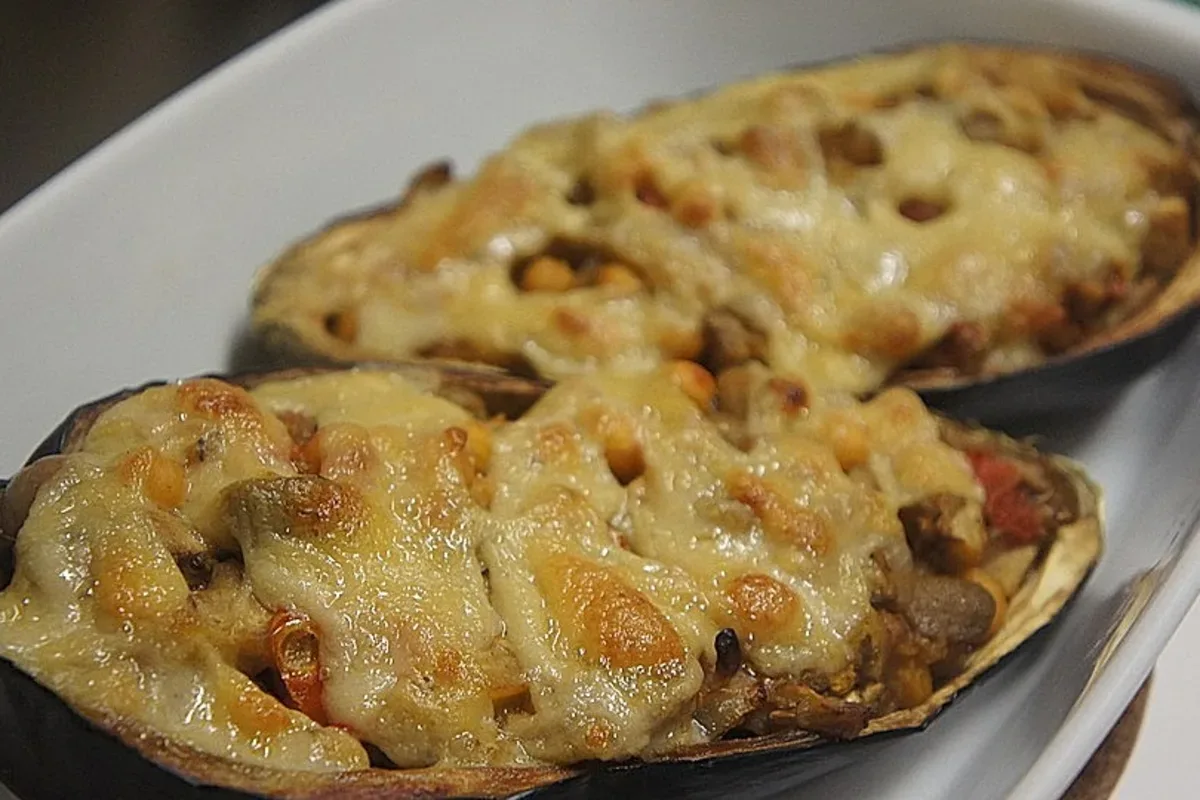 Goldener Hefeschmelz in einer Schüssel, daneben ein Holzlöffel, daneben ein Stück gebackene Lasagne