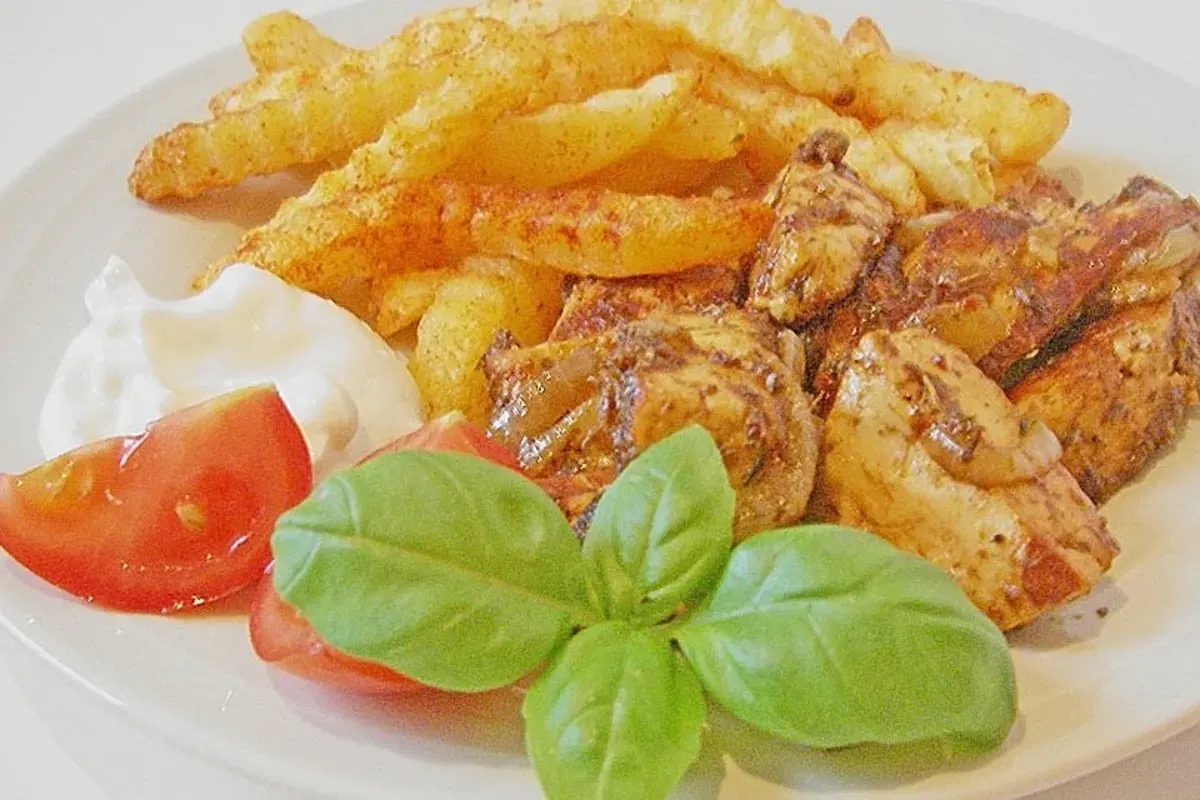 Gebratene Halloumi‑Streifen mit goldbraunen Zwiebelringen, bestreut mit Gyros‑Gewürz, serviert neben Tzatziki